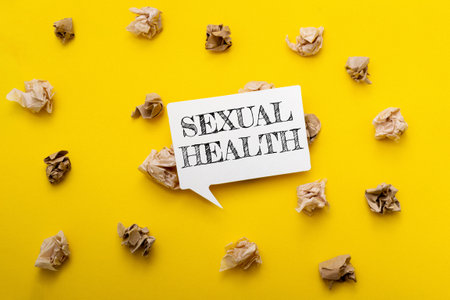 Yellow background with a white sign that says Sexual Health. The sign is surrounded by shredded paperの写真素材