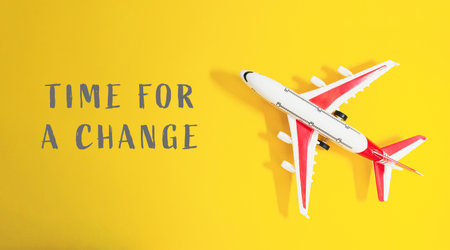 A small airplane is on a yellow background with the words Time for a Change written below itの写真素材