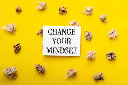 Change your mindset. The paper is on a yellow background. There are many pieces of paper scattered around the paperの写真素材