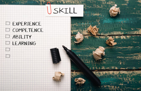 Piece of paper with a marker on it and a list of skills. The paper is on a table with a pile of crumpled paper on top of itの写真素材