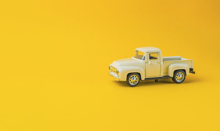A toy truck is sitting on a yellow background. The yellow background gives the image a bright and cheerful moodの写真素材