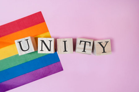 A rainbow flag and a wooden block with the word unity written on it. The flag is colorful and vibrant, while the wooden block is simple and plain. The combination of the two creates a sense of harmonyの写真素材