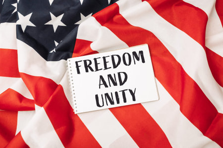 White piece of paper with the words freedom and unity written on it is placed on top of a red and...
