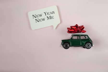 A green toy car with a red bow on top of it. The car is on top of a white sign.の写真素材