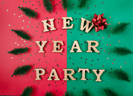 A green and red background with a bow on it. The words New Year Party are written in wooden lettersの写真素材