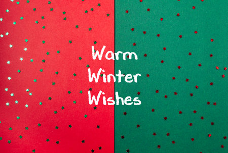A red and green background with stars and the words warm winter wishes written in whiteの写真素材