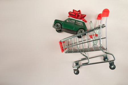 Toy car is on top of a shopping cart. The car is green and the cart is silverの写真素材