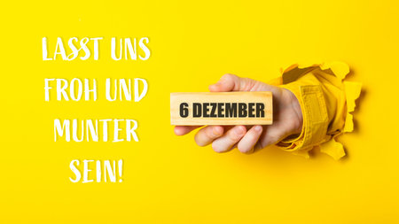 Person holding a block of wood with the words Lass uns froh und munter sein written on a yellow...
