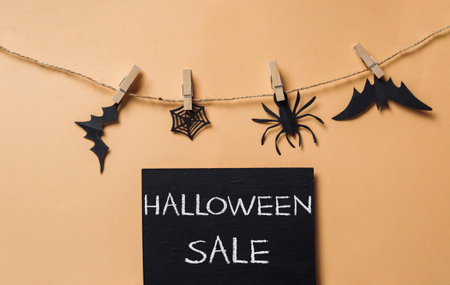Halloween sale sign with black bats, spiders and a black and white spider. The sign is hanging from a stringの写真素材