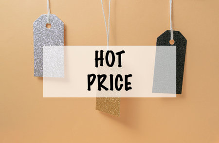 Three tags hanging from a string with the words hot price written below them. The tags are silver...