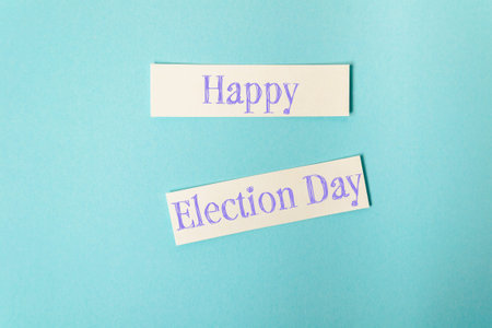 Two pieces of paper with the words Happy Election Day written on them. The paper is cut in half,...