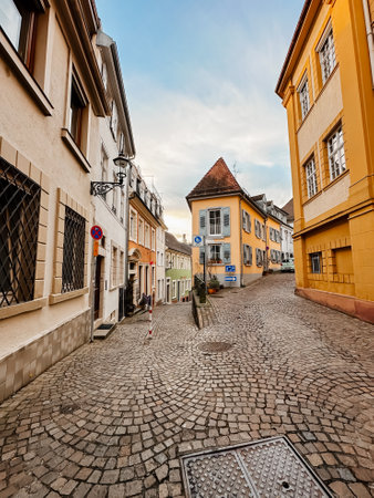 A cobblestone street with a blue sign on the side. The street is lined with yellow buildingsの写真素材