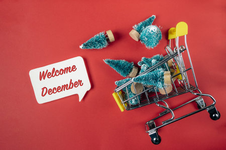 Cart full of Christmas trees is on a red background with the words welcome December written above it