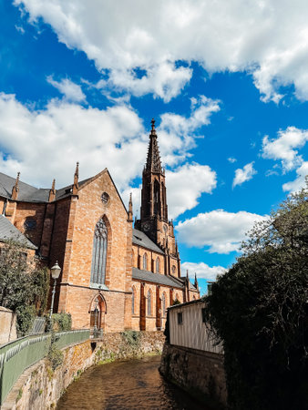 A church with a tall steeple and a blue sky. The sky is partly cloudy. The church is surrounded by a brick wallの写真素材