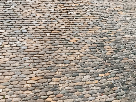A stone wall with a pattern of small stones. The wall is gray and brown in color. The stones are arranged in a way that creates a sense of depth and textureの写真素材