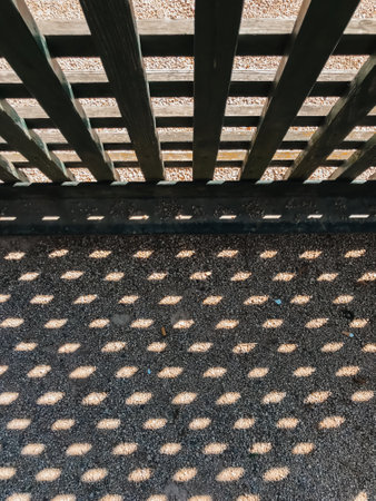 A shadow of a wooden fence on a concrete floor. The shadow is made up of many small dots, creating a pattern that is both interesting and uniqueの写真素材