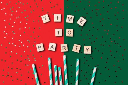 Festive scene with a red and green background, and a large pile of confetti. The words Time to Party are written in wooden blocks, adding to the celebratory atmosphereの写真素材