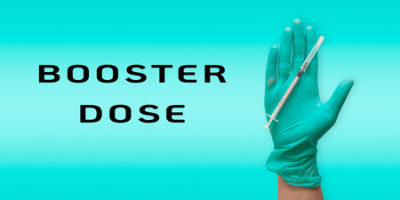 Hand holding a syringe with the words Booster Dose written below itの写真素材