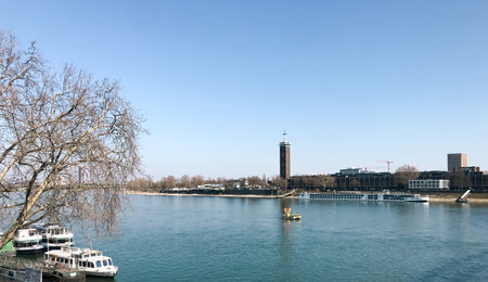 Calm river with a few boats floating on it. The sky is clear and blue