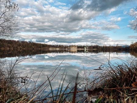 Lake with a cloudy sky in the background. The water is calm and the reflection of the sky can be seen on the surfaceの写真素材