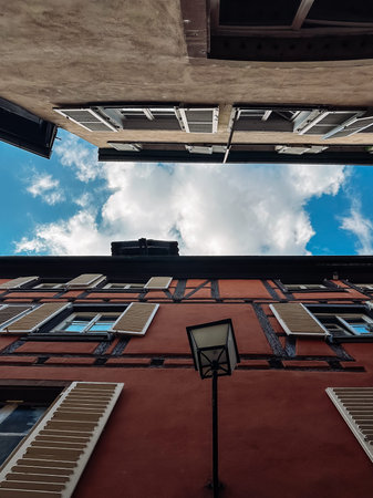 Street view of a city with a cloudy sky and a lamp post. The street is lined with buildings with...