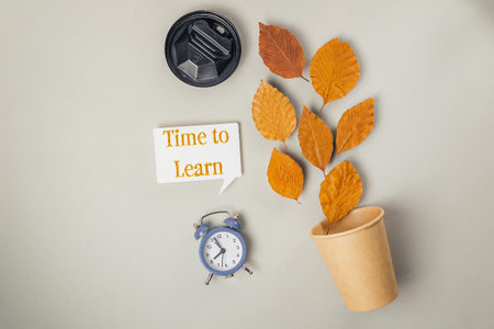 Clock and a cup of coffee are on a table with a leafy plantの写真素材