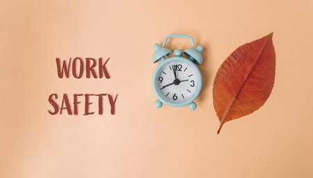 Clock with the hands on the numbers 3 and 9. The clock is on a leaf. The word work safety is written...