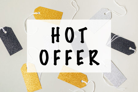 Collection of tags with the word HOT OFFER on them. The tags are gold and black. The tags are scattered on a white backgroundの写真素材