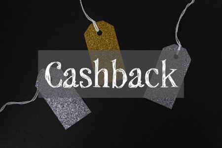 Three tags with glitter on them are hanging from a string. The tags say Cashback and are hanging from a black backgroundの写真素材