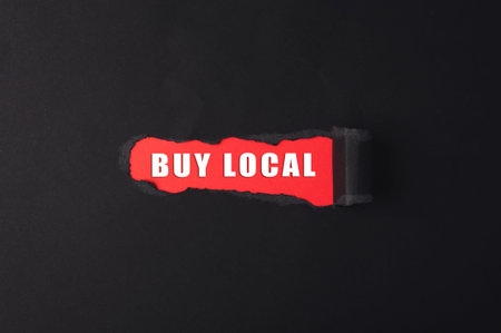 Red and black sign that says Buy Local. It is torn in halfの写真素材