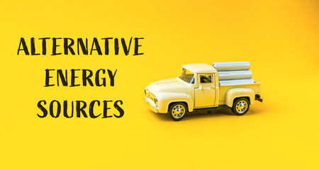 Toy truck is on a yellow background with the words alternative energy sources. The truck is yellow...