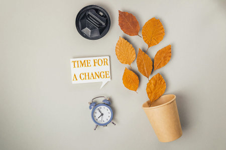 Clock is on a table next to a cup and a leafy plant. The clock reads 10:30