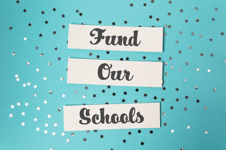 Three white pieces of paper with the words fund Our Schools written on them. back to school concept