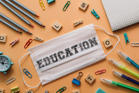 White mask with the word education written on it. The mask is on top of a table with various office...