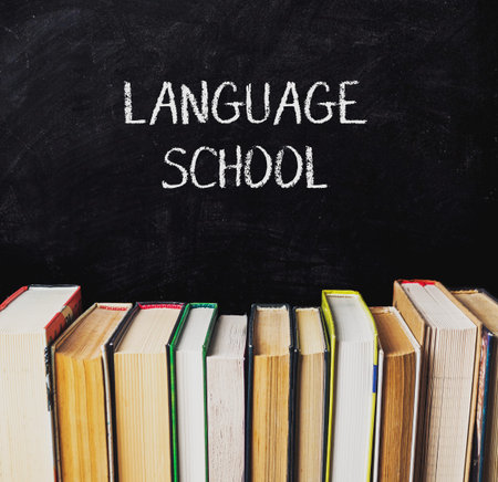 Blackboard with the words language school written on it. There are several books stacked on top of the board