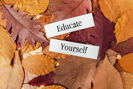 Pile of leaves with the words educate yourself written on them. The leaves are brown and scattered...