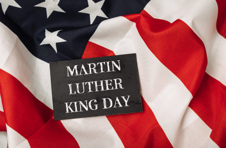 Black sign with the words Martin Luther King Day written on it. The sign is placed on top of a red...