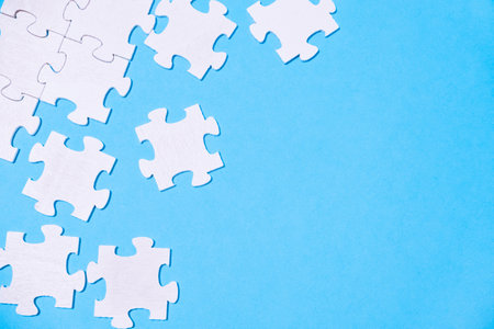 Blue background with white puzzle pieces scattered across itの写真素材