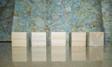 Wooden block is placed on a table next to a map. The blocks are arranged in a row, and the map is...