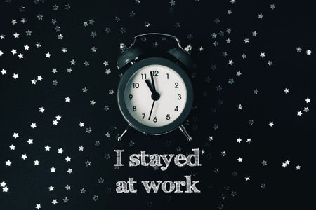 Vintage alarm clock positioned on a dark surface surrounded by scattered silver stars, featuring motivational text that emphasizes dedication and hard work in a visually appealing arrangementの写真素材