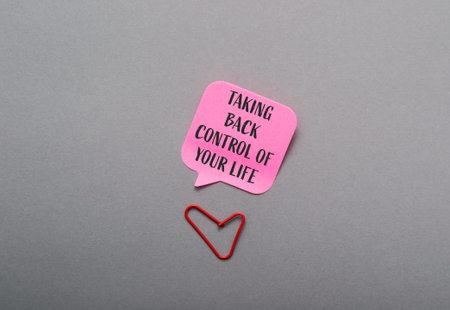 Motivational quote in pink speech bubble with red heart paperclip on gray surface, symbolizing...