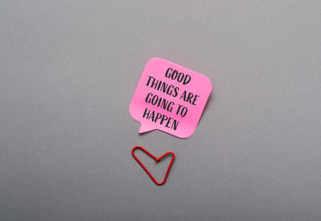 Colorful speech bubble featuring an uplifting message is placed above a red paperclip shaped like a heart, set against a smooth gray backdrop, creating a positive and inspiring atmosphereの写真素材