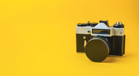 Classic vintage camera positioned against a vibrant yellow backdrop, highlighting its unique design and photography appealの写真素材