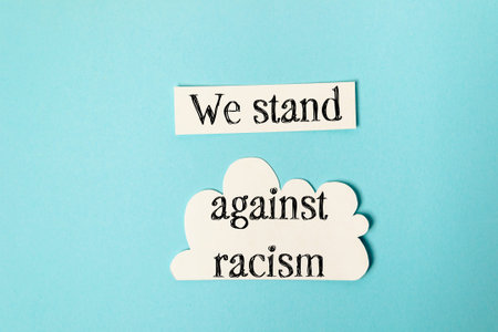 Paper cutouts display a powerful message advocating against racism, set against a soft blue...