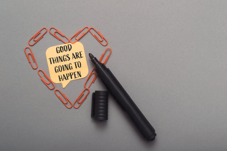 Black pen rests beside a heart made of paperclips, featuring a motivational note that reads good...
