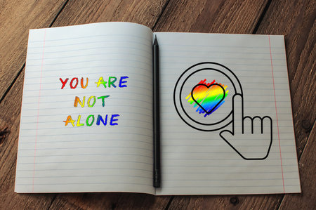 Notebook with a rainbow heart and the words You are not alone written on it. The notebook is open to...