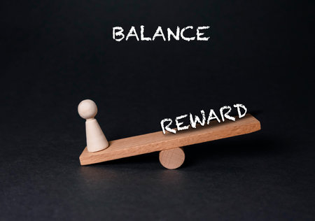A wooden balance scale features a figurine on one side, illustrating the concepts of balance and reward in a minimalistic settingの写真素材