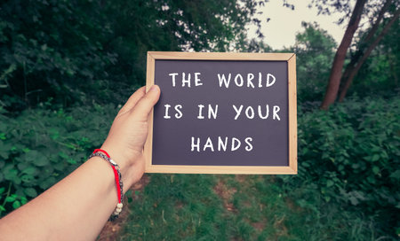 Person holding a sign that says The world is in your hands. The image conveys a message of...