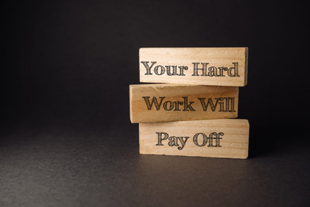 Inspirational wooden blocks stacked together display a motivational phrase about hard work and...