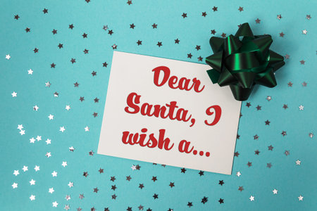 Festive greeting card featuring red lettering and a green bow, surrounded by silver stars on a blue background, ideal for holiday cheerの写真素材